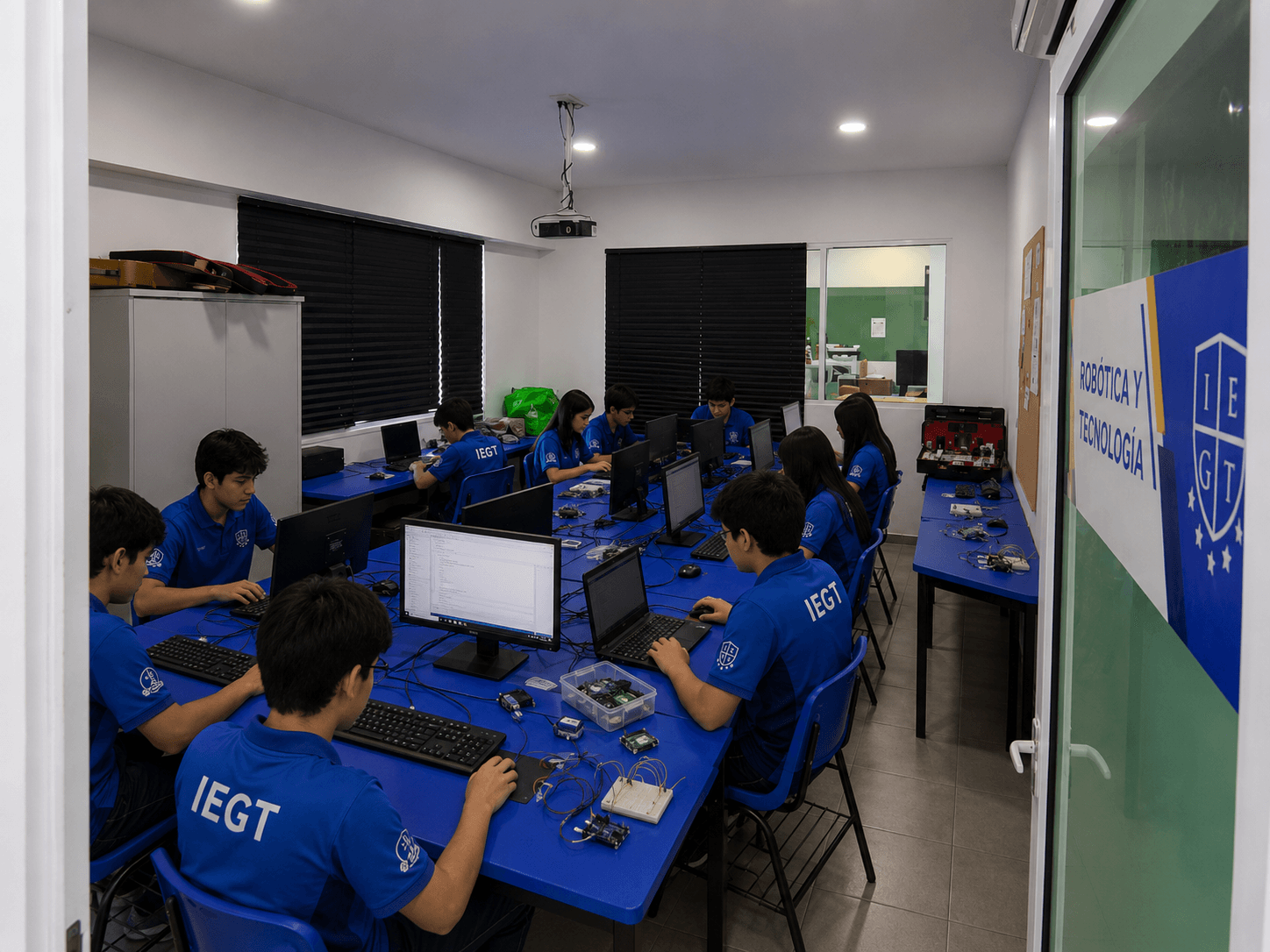 Estudiantes trabajan con computadoras y componentes electrónicos en el salón de robótica